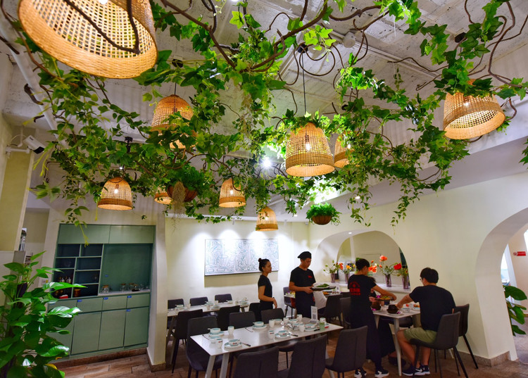 餐厅主打慢文艺色彩,藤蔓绕上屋顶,竹艺灯饰穿插在绿植之中,像极了